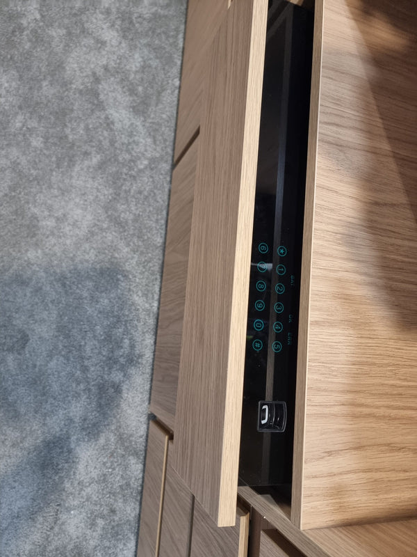 Close-up of the drawer safe keypad and fingerprint reader behind open wardrobe doors